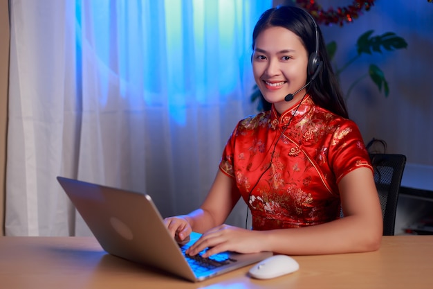 Asian businesswoman in headset speaking by conference call and video chat on laptop