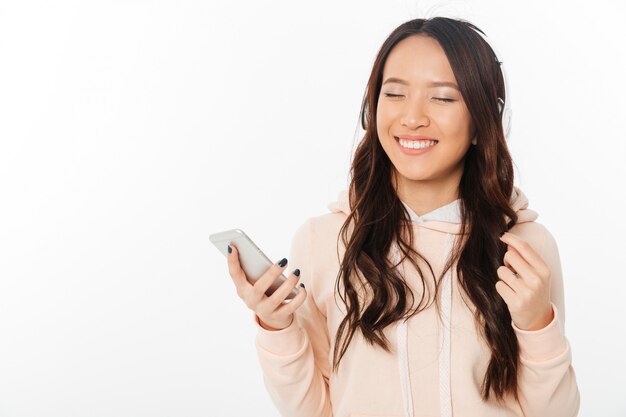 Asian cheerful woman listening music with headphones.