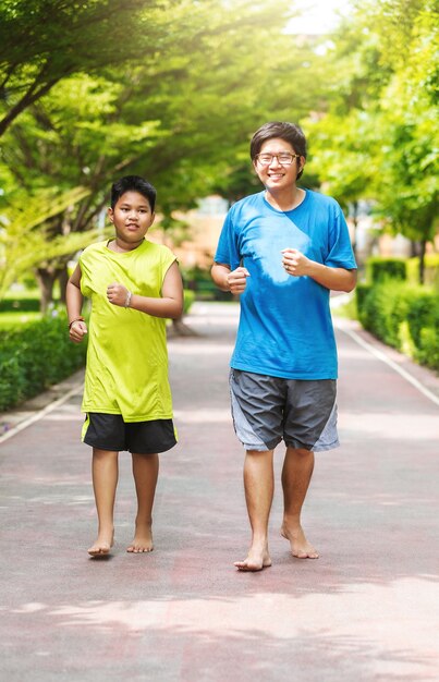 兄弟のアジア人のカップルが一緒に公園で走る。