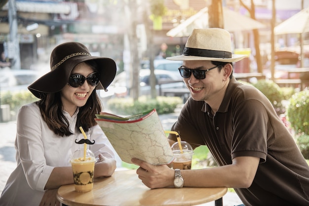 Asian couple enjoy traveling sitting at coffee shop 