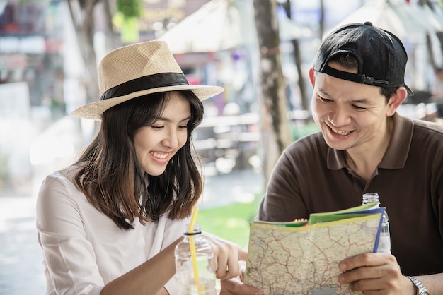 Free photo asian couple enjoy traveling sitting at coffee shop