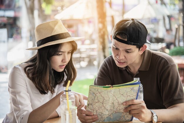 Asian couple enjoy traveling sitting at coffee shop 