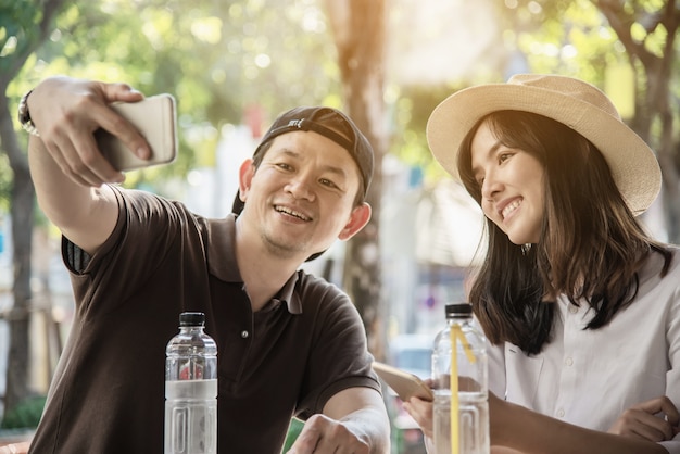 アジアのカップルはコーヒーショップで座って旅行を楽しむ