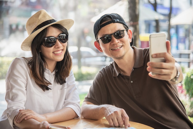 アジアのカップルはコーヒーショップで座って旅行を楽しむ