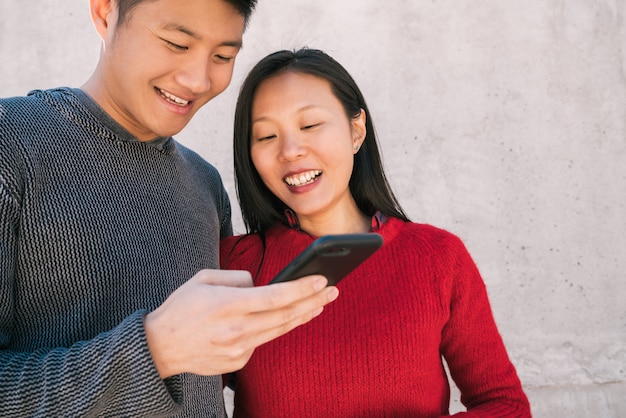 Free photo asian couple looking at the mobile phone.