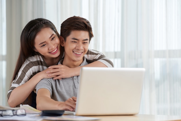 Asian couple spending weekend together having a video call with friends living abroad