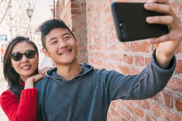 Asian couple taking a selfie with mobile phone.