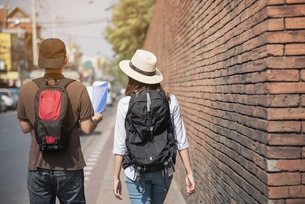 Asian couple tourist holding city map crossing the road 