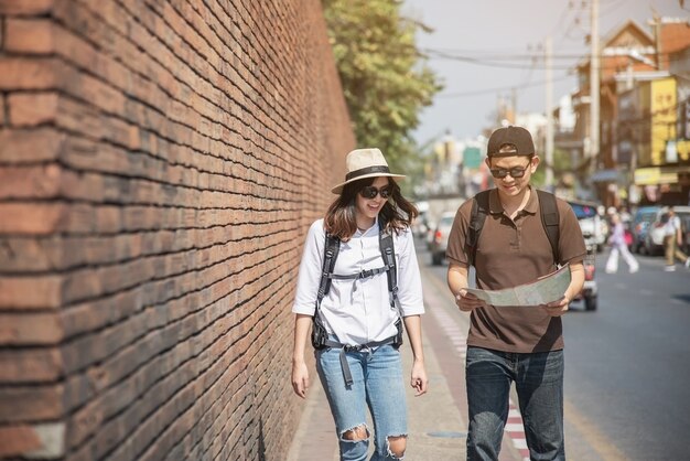 Asian couple tourist holding city map crossing the road 