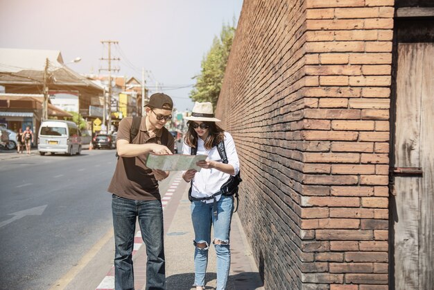 Asian couple tourist holding city map crossing the road 