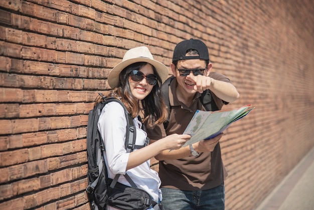 Asian couple tourist holding city map crossing the road 