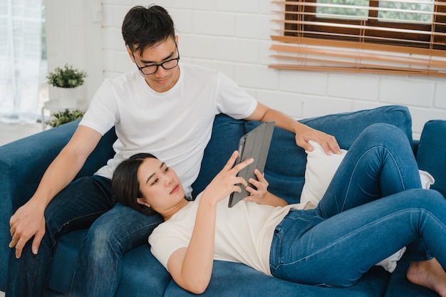 asian couple using tablet for online shopping in internet in living room at home