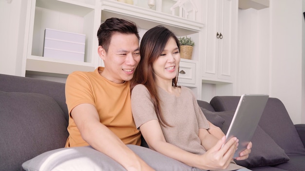 태블릿을 사용하는 아시아 부부 비디오 집에서 거실에서 친구와 전화