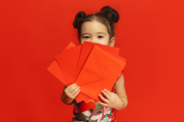 伝統的な服の赤い壁に分離されたアジアのかわいい女の子
