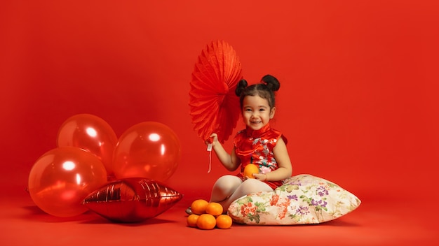 Asian cute little girl on red wall in traditional clothing