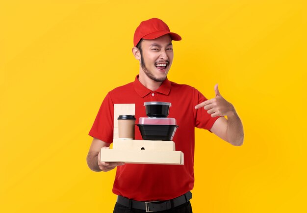 Asian delivery man wearing in red uniform holding lunch box and takeaway coffee isolated over yellow space