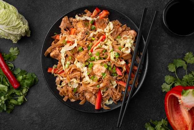 Азиатское блюдо на тарелке с палочками для еды и овощами