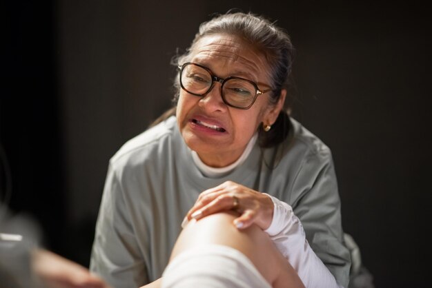 Asian doula helping woman deliver baby. Grey-haired woman in senior talking to patient giving birth. Home birth concept