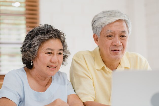 Азиатская пожилая пара с помощью ноутбука конференции с врачом о медицине информации в гостиной