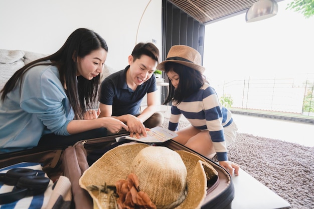 Concetto di viaggio in famiglia asiatica felicità papà mamma figlia imballaggio e pianificazione per un viaggio di vacanza con eccitato e gioioso