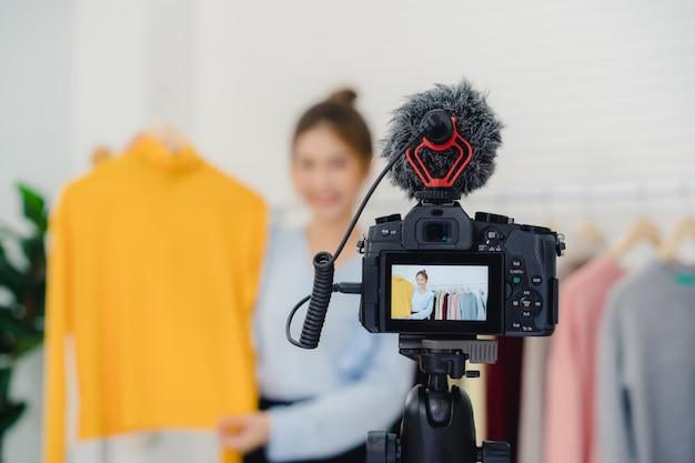 Influencer online di blogger femminile della moda asiatica che tiene i sacchetti della spesa e molti vestiti