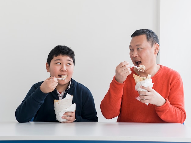 アジアの父と息子のファーストフードを食べる