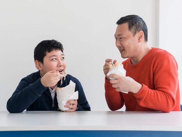 アジアの父と息子が室内で食べる