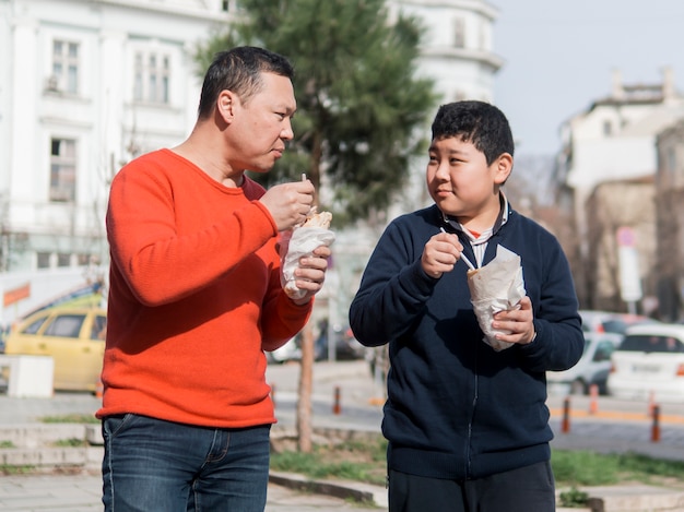 Foto gratuita padre e figlio asiatici che mangiano all'aperto