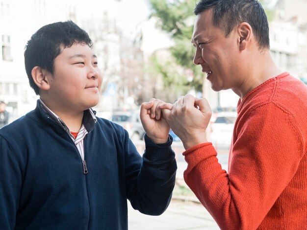 Asian father and son holding little fingers