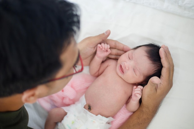 アジアの父は彼の愛らしい生まれたばかりの赤ちゃんを慎重に世話します
