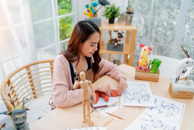 아시아 여성 예술가 arttoys 점토 조각은 그녀의 취미 점토 조각을 위해 주말 하루를 보내고 집에서 점토 조각상을 집에서 캐주얼한 생활 방식으로 만드는 동안 형태 얼굴 해부학을 적절하게 정의합니다.