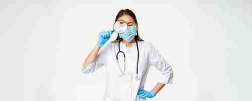 Free photo asian female doctor looking through magnifying glass examine patient searching disease wearing medic