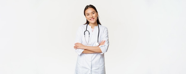 Free photo asian female doctor physician in medical uniform with stethoscope cross arms on chest smiling and lo