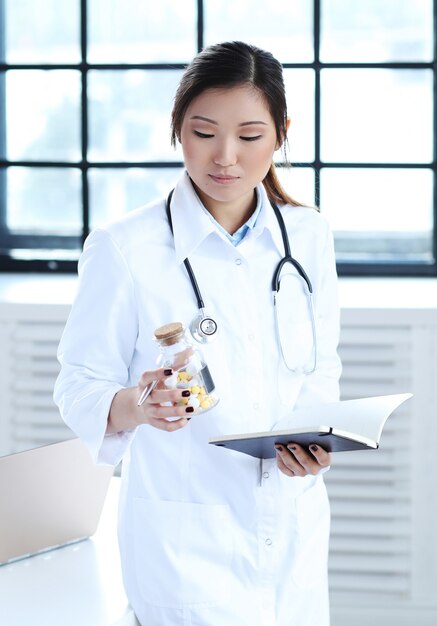 Asian female doctor, woman specialist with notebook and pills