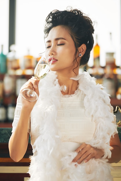 Бесплатное фото Азиатский женский гость, наслаждаясь бокалом шампанского на вечеринке в баре