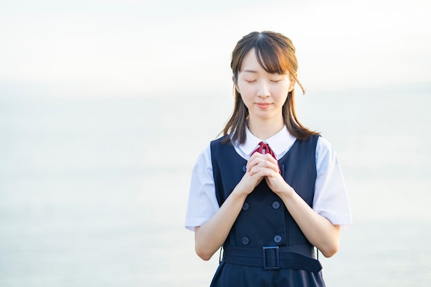 祈りのポーズでアジアの女子高校生が屋外でポーズ プレミアム写真