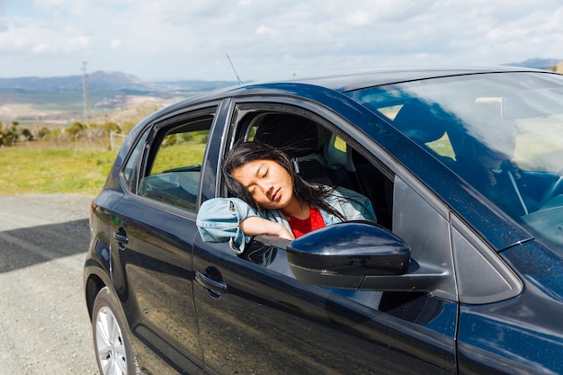 アジアの女性が車で寝ています。