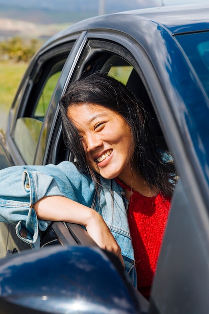 Foto gratuita seduta sorridente femminile asiatica in automobile