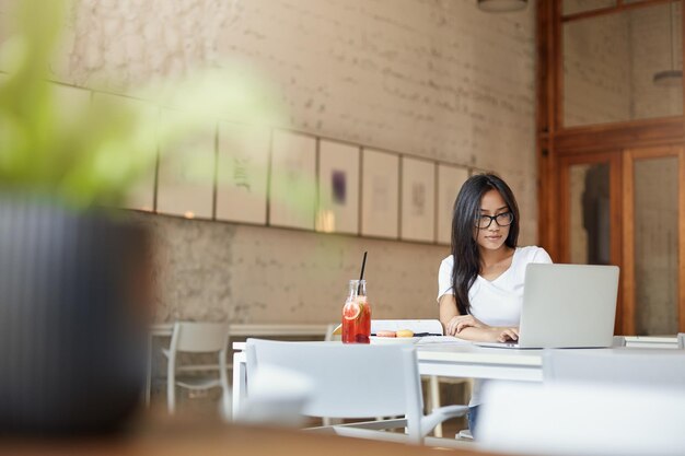 Asian female startup entrepreneur working in open space cafe Wide shot negative space Student learning in campus