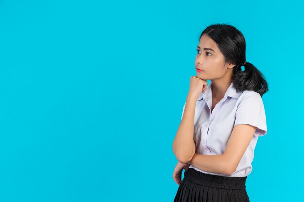 Asian female students performing various gestures on a blue .