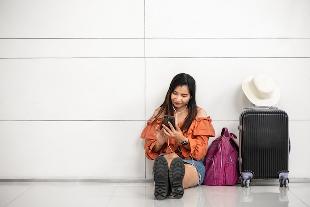 공항에서 라운지 외부의 스마트 폰을 사용하여 비행기를 기다리는 아시아 여성 여행자