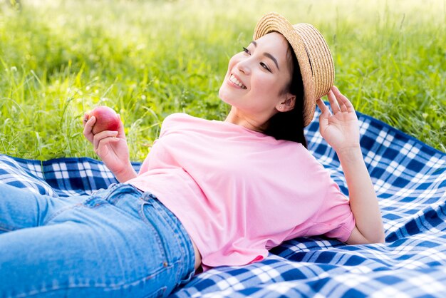 Азиатская женщина с яблоком, лежа на ткани