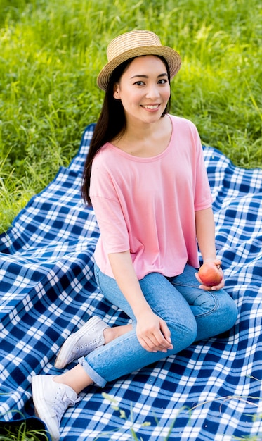 Asian female with apple sitting on plaid