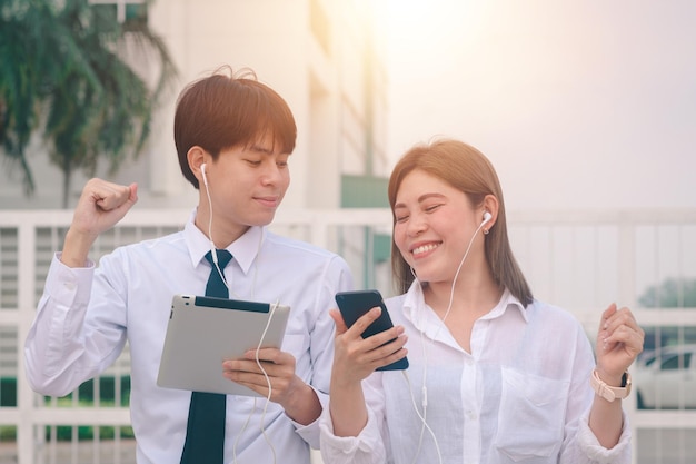 携帯​電話​の​音楽​に​満足している​アジア​の​友人​屋外​の​友人​は​スマート​フォン​の​使用​技術​を​一緒​に​リラックス