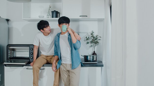 アジアの同性愛者のカップルがコーヒーを飲んで、家で楽しい時間を過ごします。幸せなリラックスした話を話している若いハンサムなLGBTQ +男性は一緒に朝の家でモダンなキッチンでロマンチックな時間を過ごします。