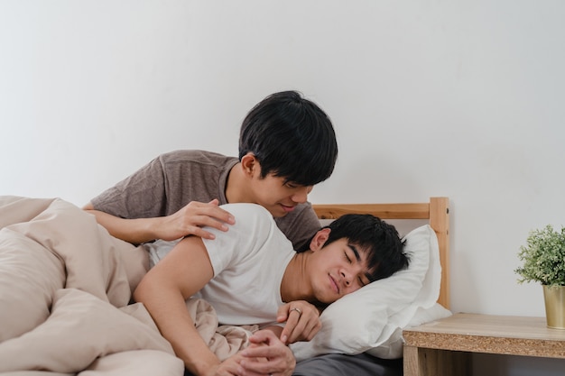 Asian gay couple kiss and hug on bed at home. young asian lgbtq men happy relax rest together spend romantic time after wake up in bedroom at home in the morning .