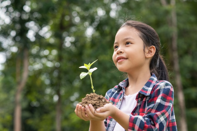 Asian girl holding plant and soil
