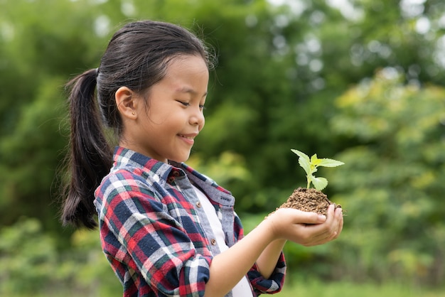 植物と土壌を保持しているアジアの女の子