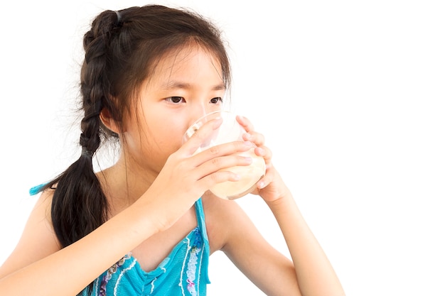 Asian girl is drinking a glass of milk over white background