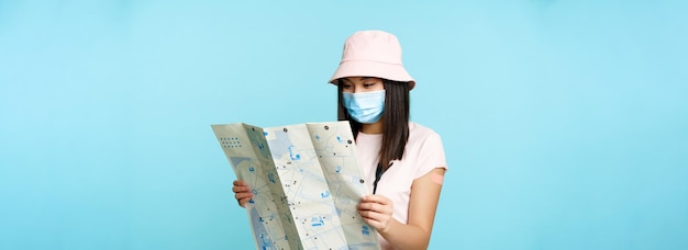 Азиатская девушка-туристка в медицинской маске, вакцинированная от ковида, с пластырем на руке, путешествующая за границу, вот